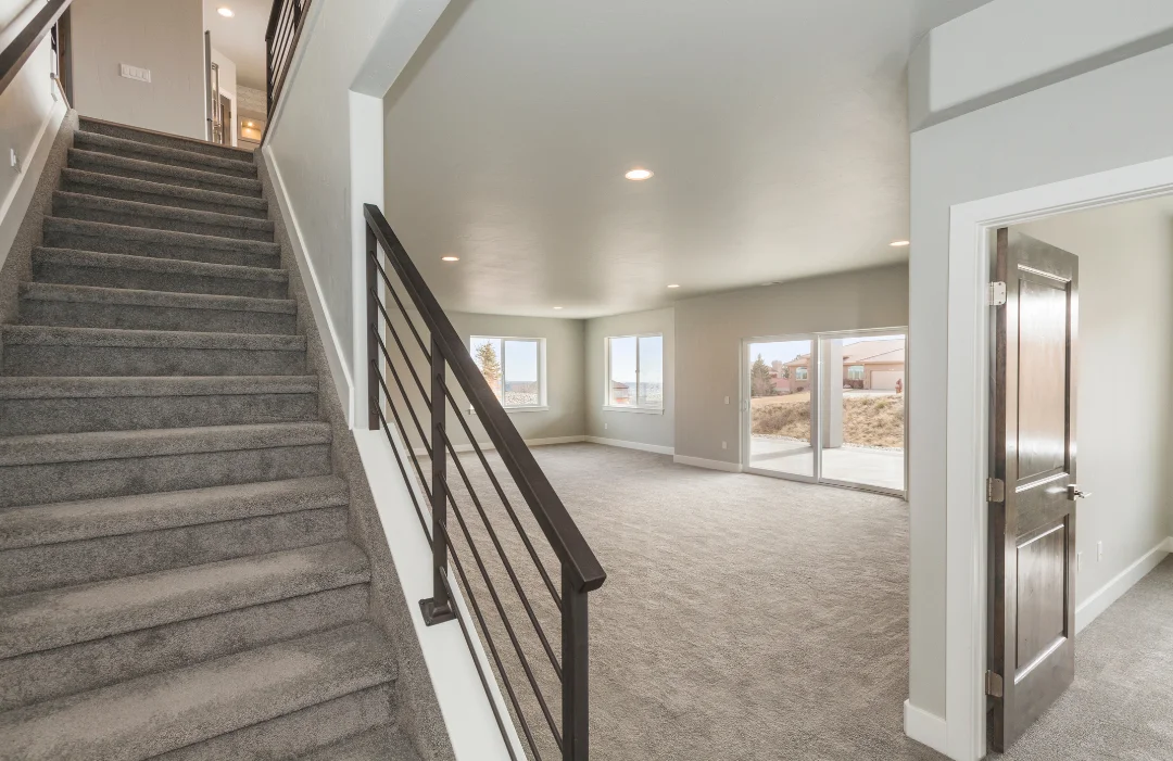 Finished basement with wrought iron spindles on staircase and glass doors to the outside patio