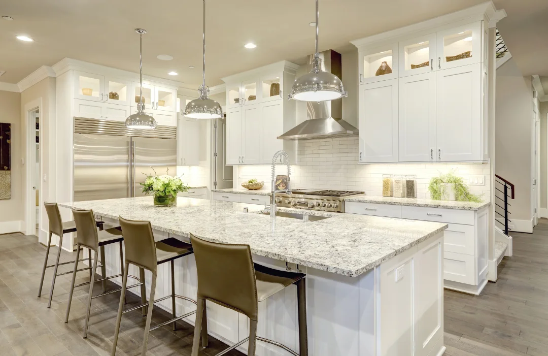 A white, luxury kitchen with stainless accents and appliances, white marble counters