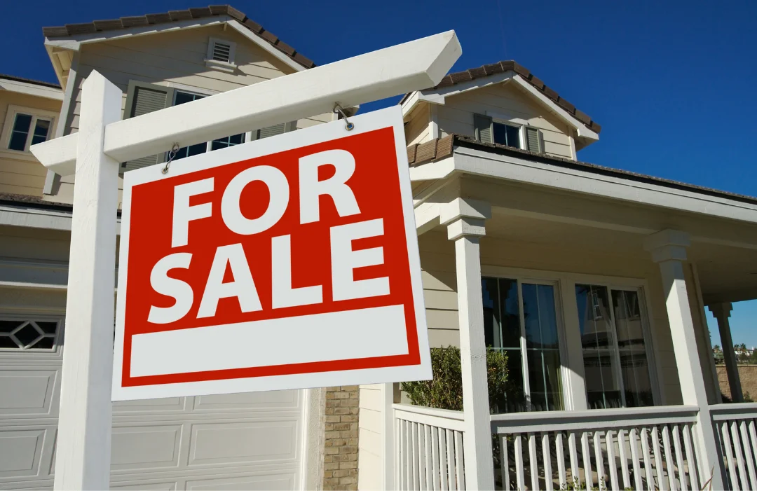 A home with a porch and a second story with a For Sale sign in fromnt of it