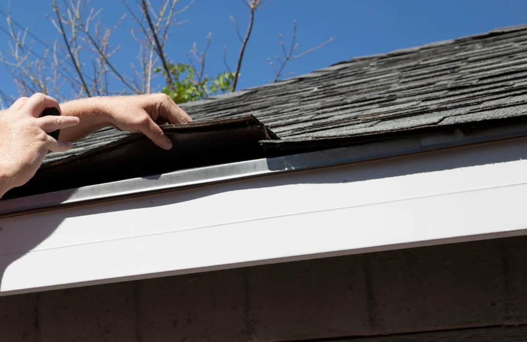 A man checking under a roof tile taking a pic with smartphone