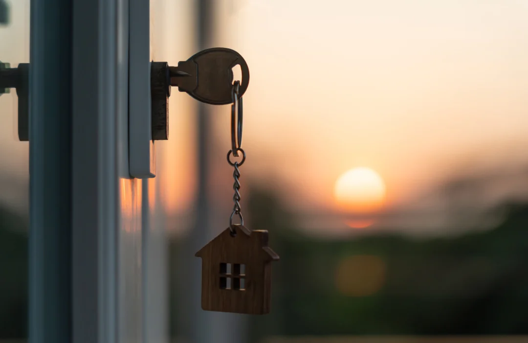 Door key in the lock of a house, hanging in the sunset